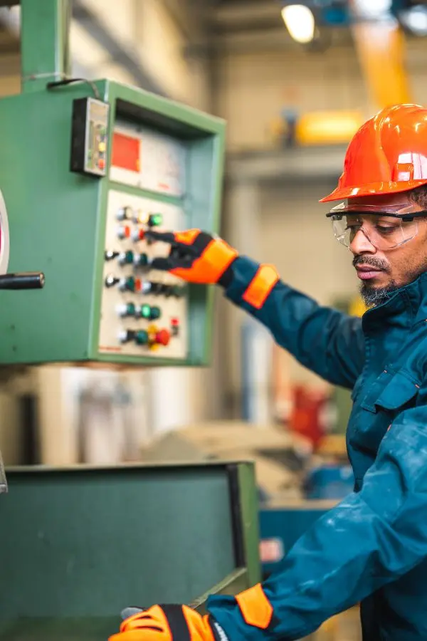 lavoratore-in-fabbrica Operaio che opera su una macchina della catena di montaggio